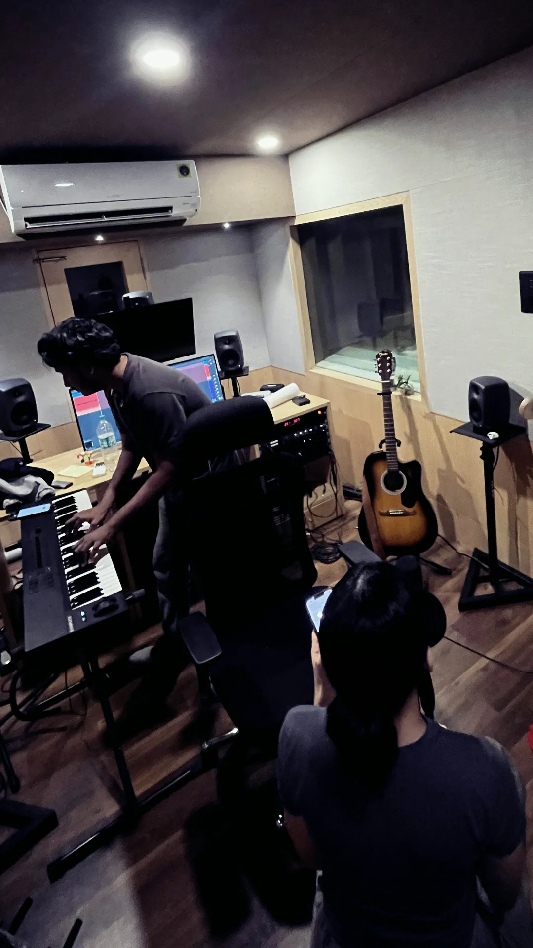 Band jamming on keys and guitar in the control room