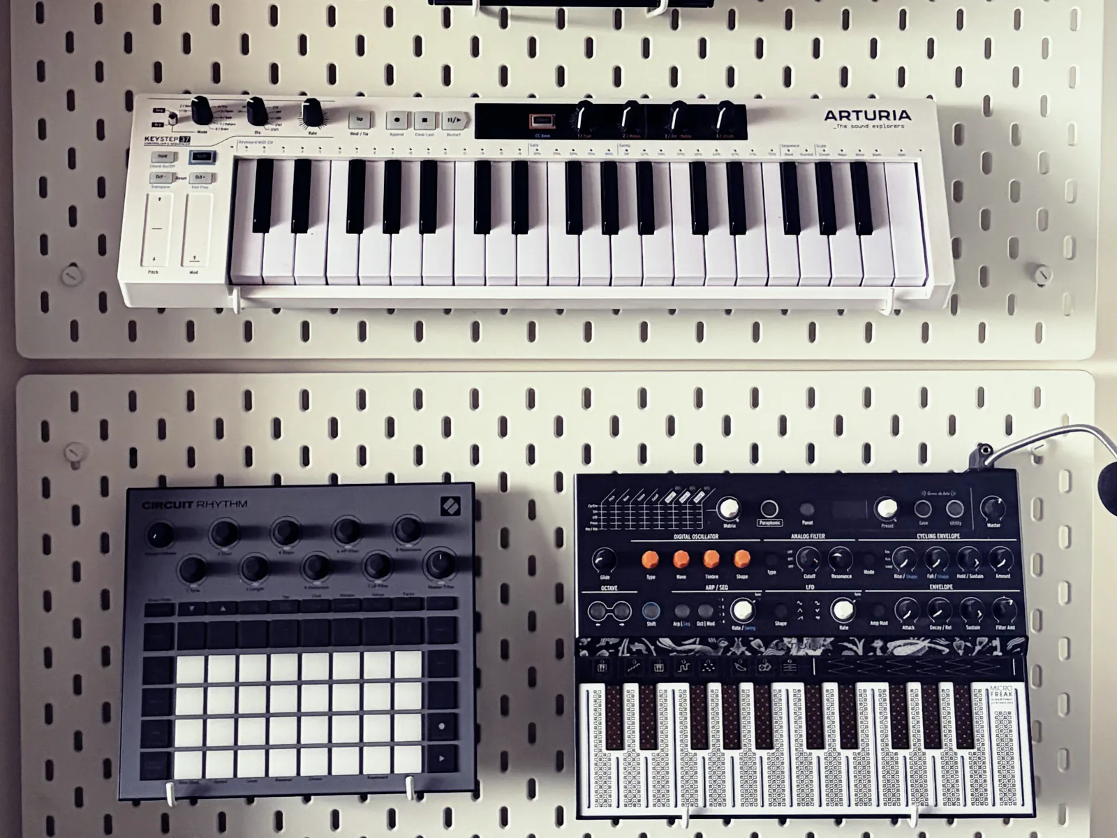 Arturia KeyStep, Novation Circuit Rhythm and Arturia MicroFreak on a pegboard wall