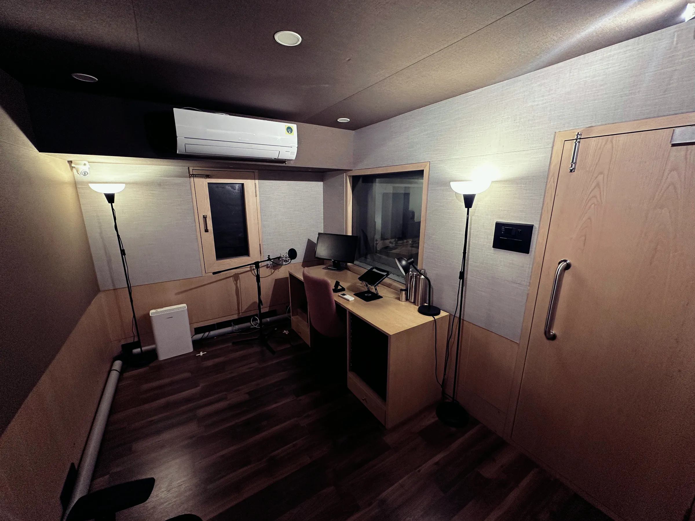 Treated recording booth with a mic stand, desk and window
